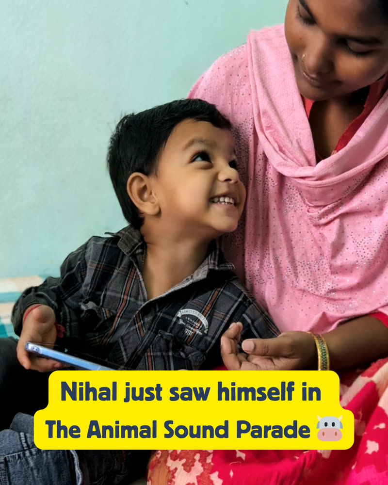 Nihal looking up in delight at his mother while reading his personalized Your Mitra storybook